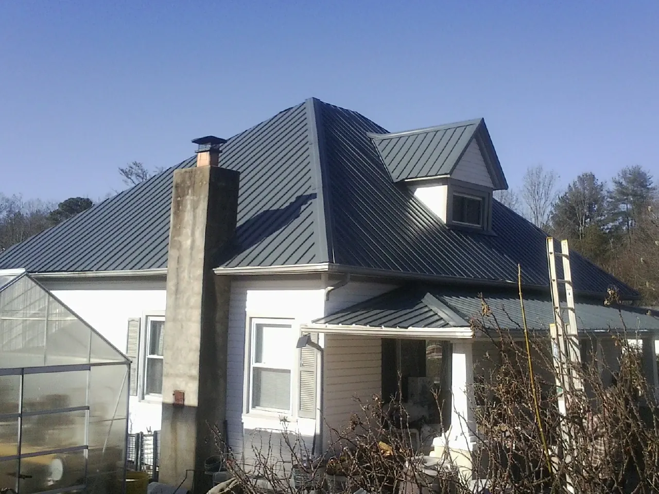 Dark blue standing seam metal roof on a white farmhouse with dormer — Slate & Tile Roof Repair by Roofing Brothers in Kennebunk