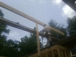 Carpenter setting a ridge beam over a new addition frame — Ice Dam Removal by Roofing Brothers in Kennebunk