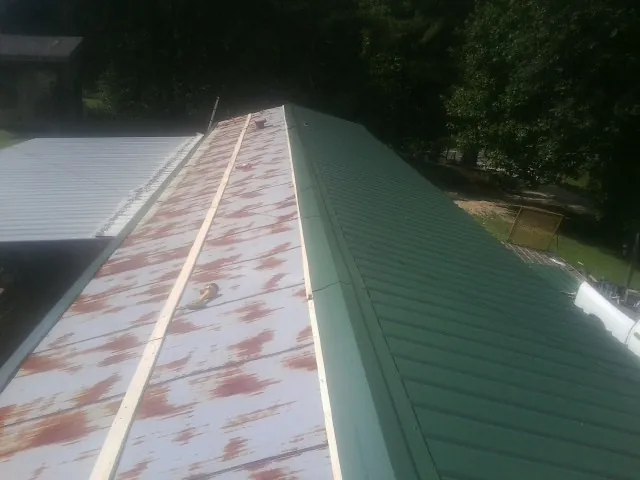 Old rusted panels beside newly installed green metal roofing — Wind Damage Roof Repair by Roofing Brothers in Kennebunk