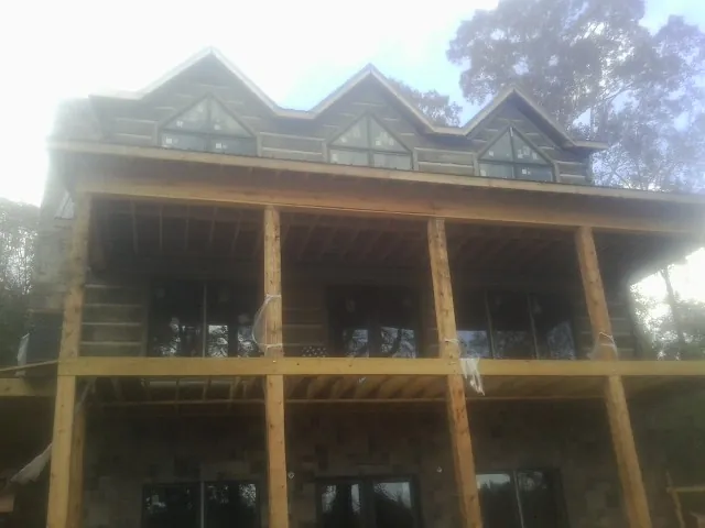 Dormers and porch framing on a large log home under construction — Roof Coating work by our crew in Kennebunk