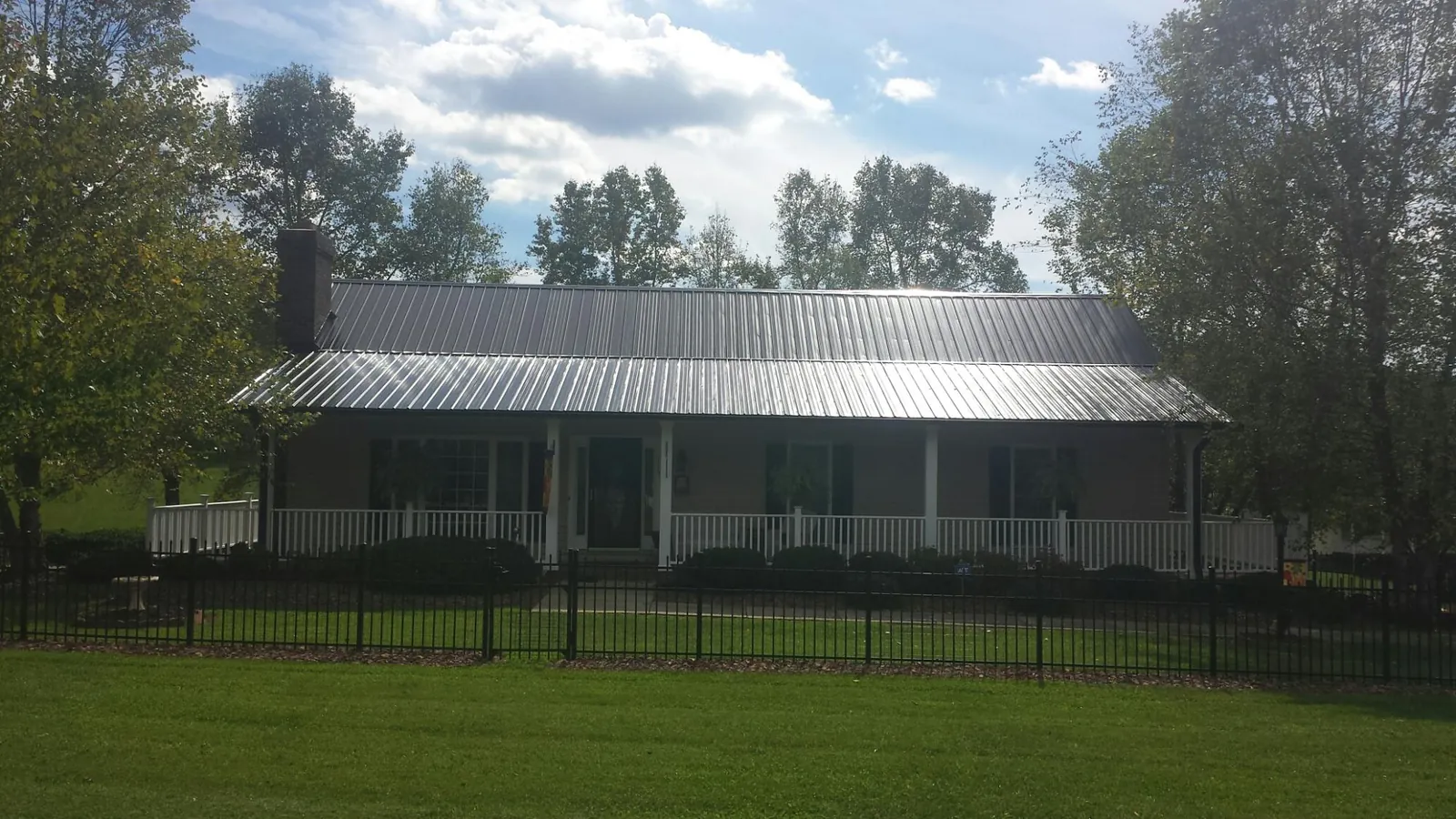 Gray metal roof on a brick ranch with a full width front porch — Gutter Guard Installation work by our crew in Kennebunk