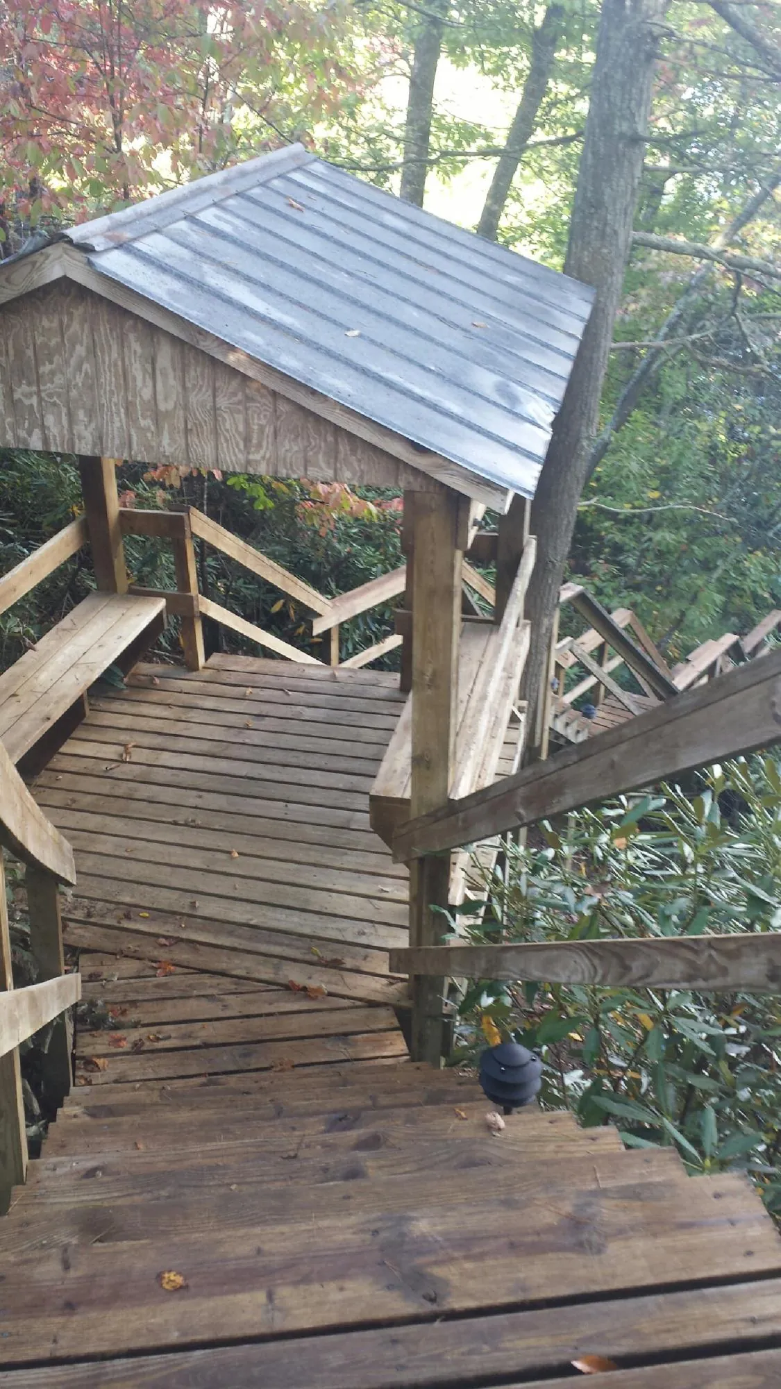 Metal roofed shelter over wooden steps on a wooded walkway — Skylight Repair & Installation work by our crew in Kennebunk