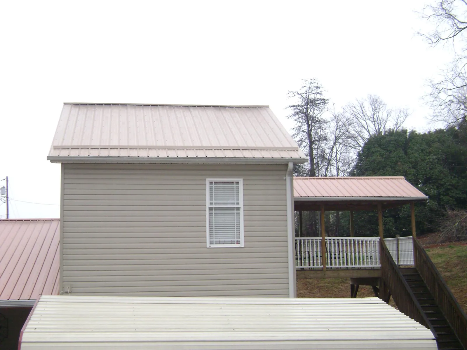 Tan metal roofs on a two story addition and attached porch, from a Roof Replacement job in Kennebunk