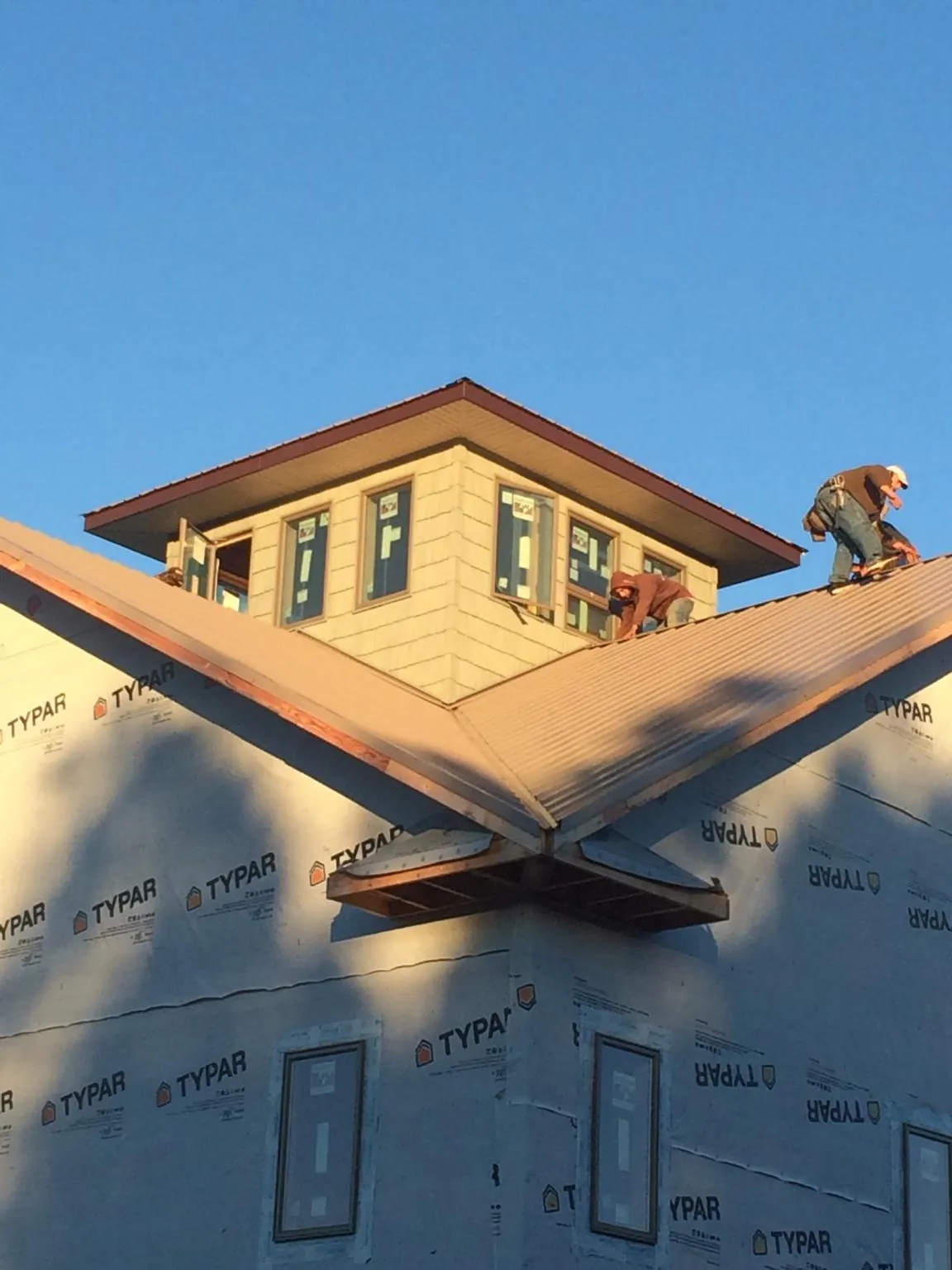 Roofers working around a rooftop cupola on a new metal roof at sunset — Roof Waterproofing in Kennebunk by Roofing Brothers